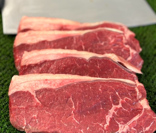 Steaks lined up on a green background